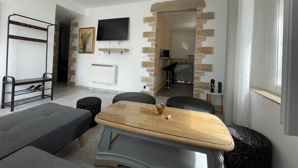 Ein modernes Wohnzimmer mit Couchtisch aus Holz, grauem Sofa und einem an der Wand befestigten Fernseher.