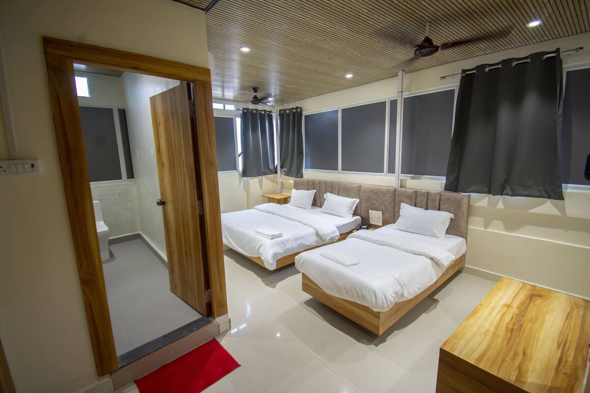 Une chambre d’hôtel moderne avec deux lits, une table basse en bois et une vue sur la ville.