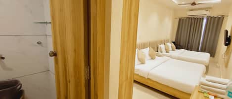 A hotel room with a wooden wardrobe, a bed with white bedding, a bedside table, and a ceiling fan.