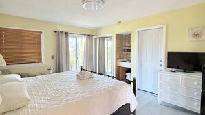 A bedroom with a bed, a dresser, a television, and a bathroom visible through an open door. - Awesome Studio at Bay Tree, 1st floor (Little River)