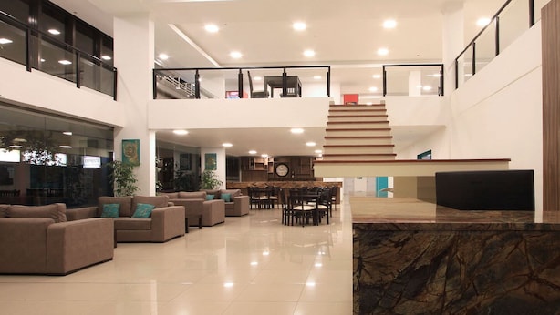 A spacious lobby with a marble reception desk, multiple seating areas, and a staircase leading to an upper floor. - Hotel Grand Prix (Villa Carlos Paz)