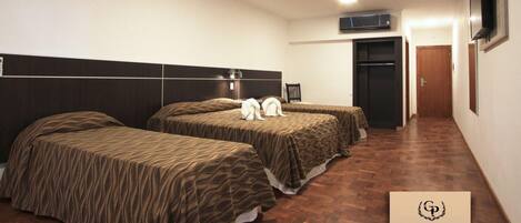 A hotel room with two beds, a flat-screen TV, and a minibar.