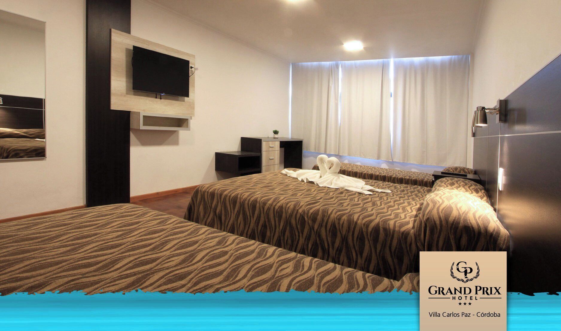 A hotel room with two beds, a TV, a desk, and a window with curtains.