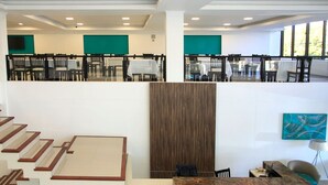 A modern hotel lobby with a staircase, dining area, and a large wooden panel wall. - Hotel Grand Prix (Villa Carlos Paz)