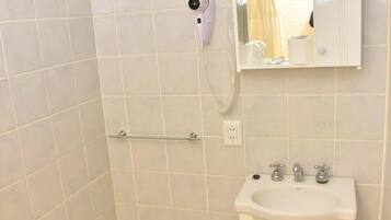 Un baño con lavamanos blanco, espejo y bidé.