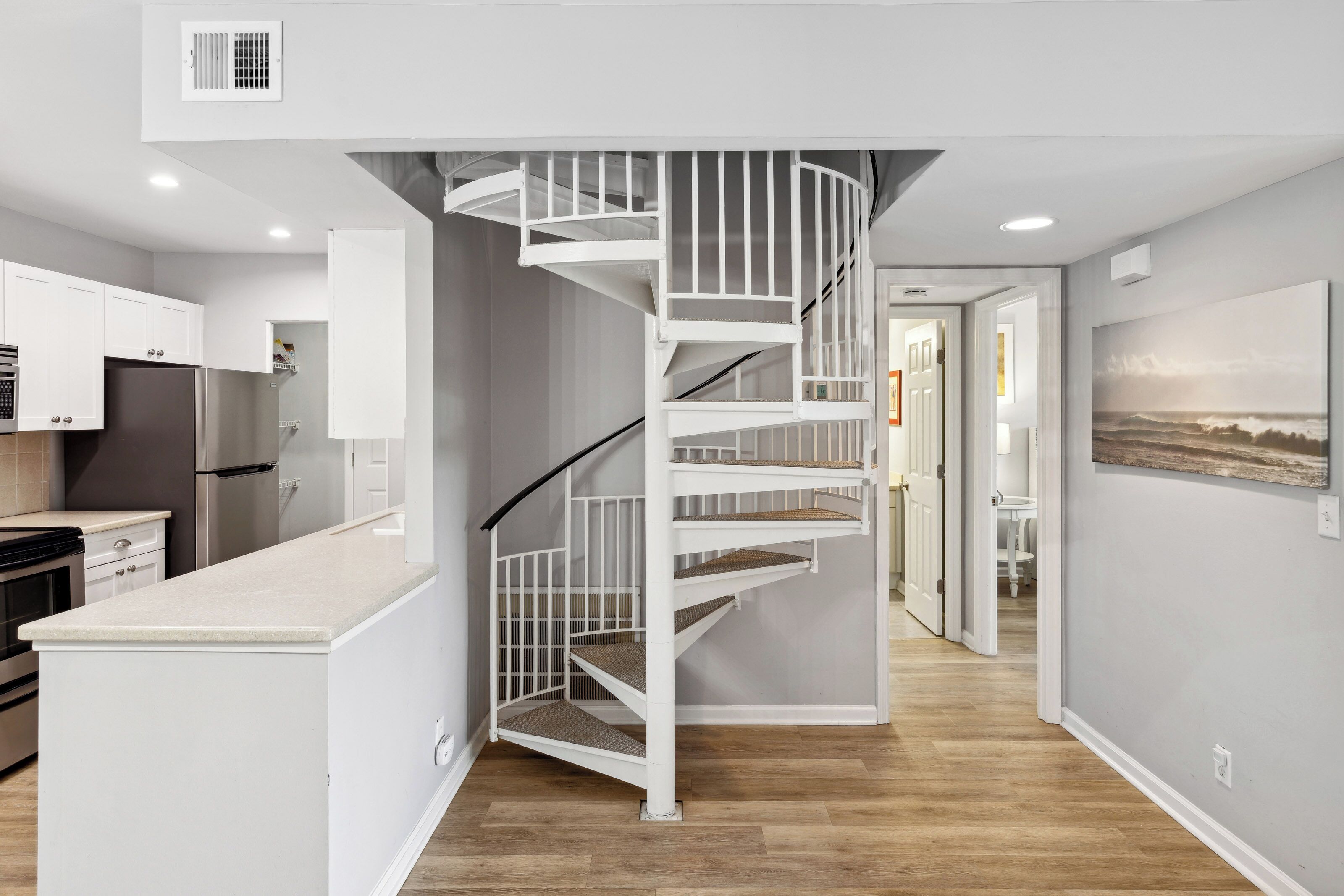 Una cocina moderna con una escalera espiral blanca que lleva a un comedor.