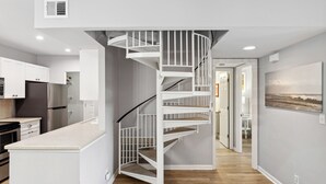 A modern kitchen with a white spiral staircase leading to a dining area. - 891 Ketch Court @ Harbour Town, Sea Pines | Walk to Marina & Golf Links | Pet-Friendly! (Hilton Head Island)
