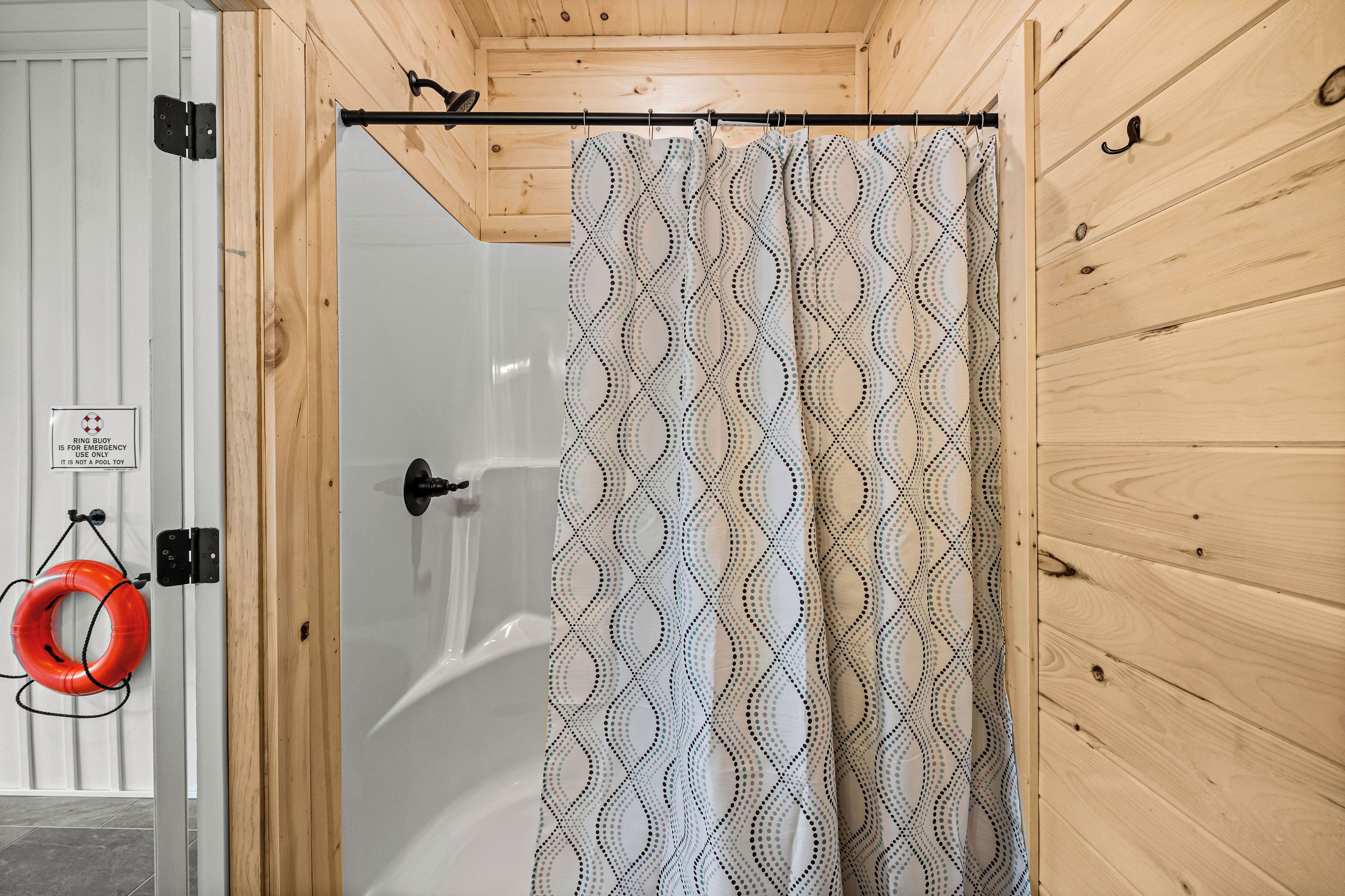 A wooden shower enclosure with a patterned shower curtain.