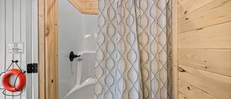 A wooden shower enclosure with a patterned shower curtain.