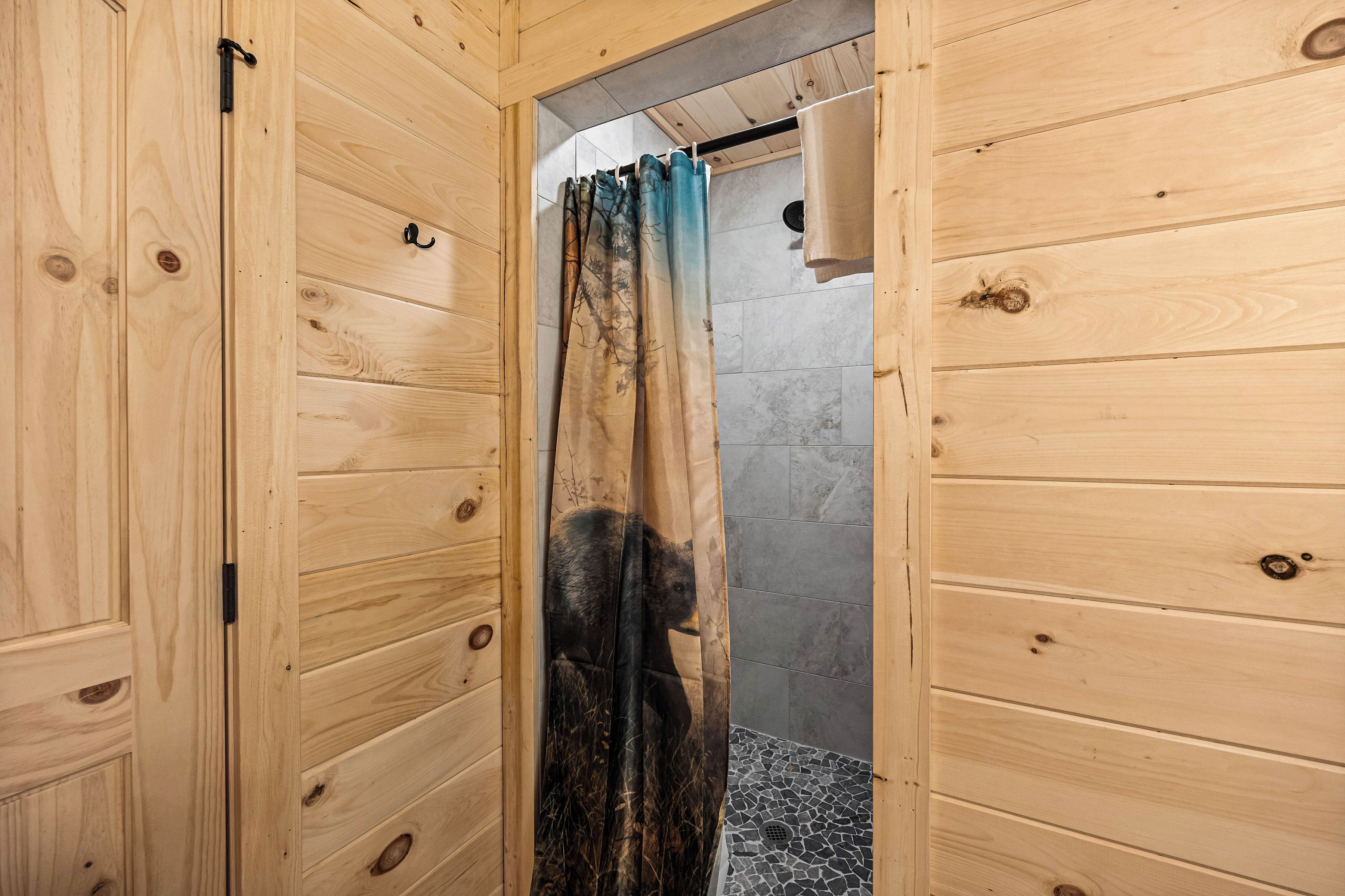 A wooden cabin bathroom with a shower curtain featuring a bear design.