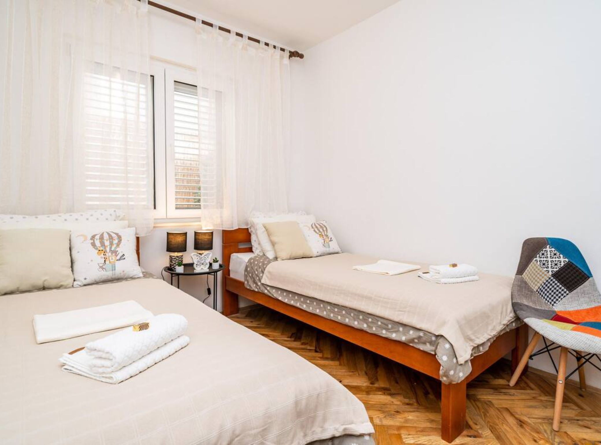 Ein Schlafzimmer mit zwei Betten, einem kleinen Tisch mit Lampen und einem Sessel.