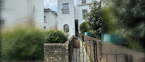 A gated entrance to a residential building with a brick wall and metal gate.