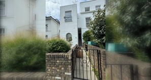 A gated entrance to a residential building with a brick wall and metal gate. - Delightful 3BD Family Home w Garden, Finsbury Park (Greater London)
