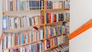 A bookshelf filled with books and a framed painting above it. - Delightful 3BD Family Home w Garden, Finsbury Park (Greater London)