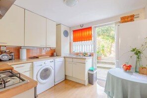 A compact kitchen with a washing machine, a sink, and a stove. - Delightful 3BD Family Home w Garden, Finsbury Park (Greater London)