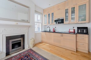 A modern kitchen with wooden cabinets, a built-in microwave, and a gas stove. - Superbly Located 1BD Flat, Heart of Fitzrovia (Greater London)