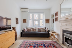 A living room with a sofa, TV, fireplace, and decorative items.