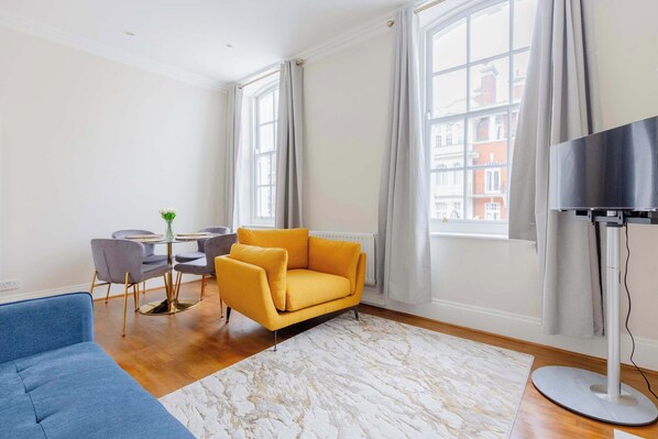 A living room with a sofa, a coffee table, a TV, and large windows.