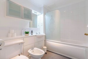A modern bathroom with a toilet, bidet, sink, and shower.