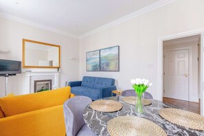 A living room with a fireplace, sofas, a TV, and artwork on the wall.