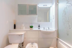 Un baño moderno con inodoro, bidé, lavamanos y espejo.