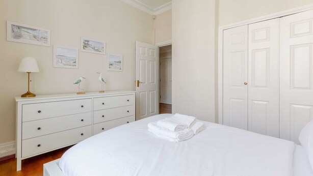 A bedroom with a bed, a dresser, a lamp, and a door. - Stylish 1BR Flat by Museums in South Kensington (Greater London)