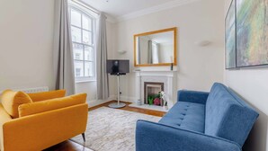A living room with a sofa, a television, a fireplace, and a large mirror. - Stylish 1BR Flat by Museums in South Kensington (Greater London)