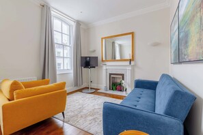 Un salon comprenant un canapé, un téléviseur, une cheminée et un grand miroir.