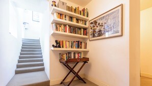 A staircase leading to a landing with a bookshelf and a framed picture on the wall. - One of a Kind 2BDR Flat in Shoreditch (London)