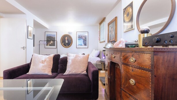 A living room with a sofa, a wooden dresser, and framed pictures on the wall. - One of a Kind 2BDR Flat in Shoreditch (London)