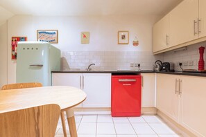 A kitchen with white cabinets, a red dishwasher, and a vintage refrigerator. - One of a Kind 2BDR Flat in Shoreditch (London)