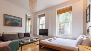 Une chambre moderne avec un lit, un canapé, une télévision et un tableau.