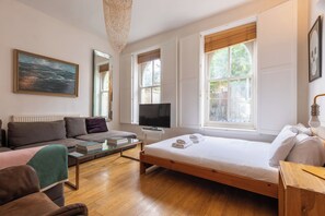 A modern room with a bed, sofa, TV, and a painting.