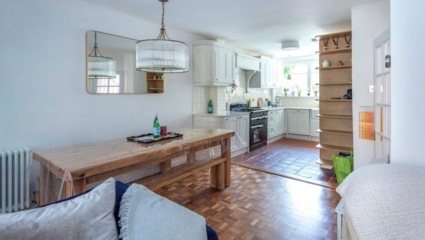 A kitchen with white cabinets, a wooden table, and a hanging light fixture.