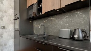 A modern kitchen with a double sink, a kettle, and a built-in oven. - Stylish Apartment in the Center | Balcony, Air Conditioning (Wrocław)