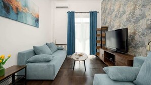 A modern living room with a sofa, a coffee table, a TV, and a painting on the wall. - Stylish Apartment in the Center | Balcony, Air Conditioning (Wrocław)