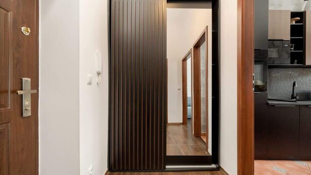 A hallway with a sliding door leading to a kitchen area. - Stylish Apartment in the Center | Balcony, Air Conditioning (Wrocław)