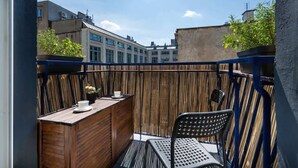 A balcony with a wooden table, a chair, and a view of buildings in the background. - Stylish Apartment in the Center | Balcony, Air Conditioning (Wrocław)