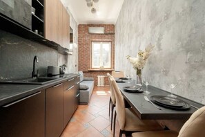 Une cuisine moderne avec un coin repas, comprenant un mur en briques, une fenêtre et une table dressée pour deux personnes.