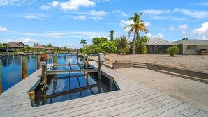 A wooden dock leading to a swimming pool with a clear blue sky above. - Island Sanctuary: Canal Home with Pool, Pets OK! (Sanibel)