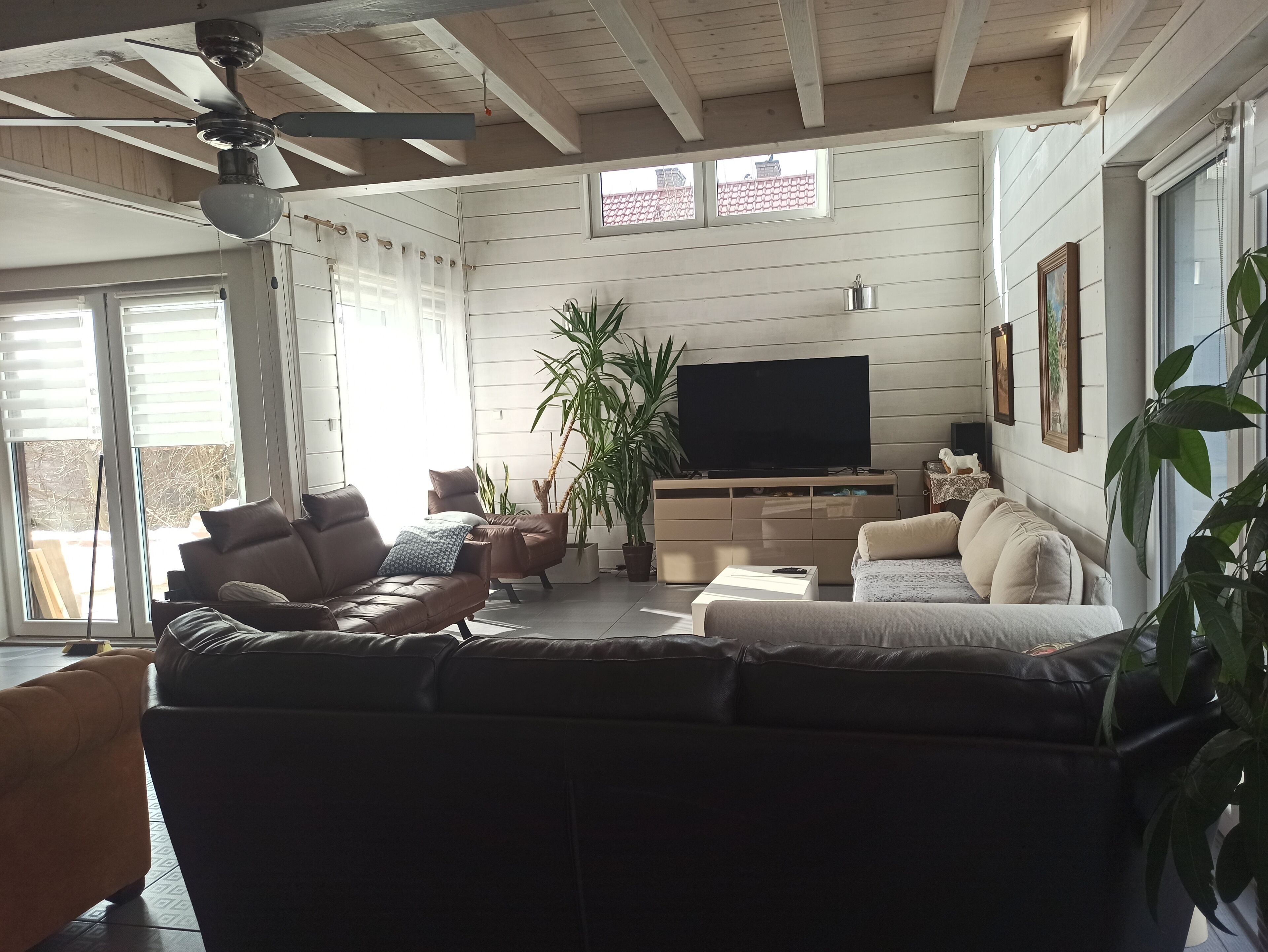 A living room with a large sectional sofa, a flat-screen TV, and a ceiling fan.