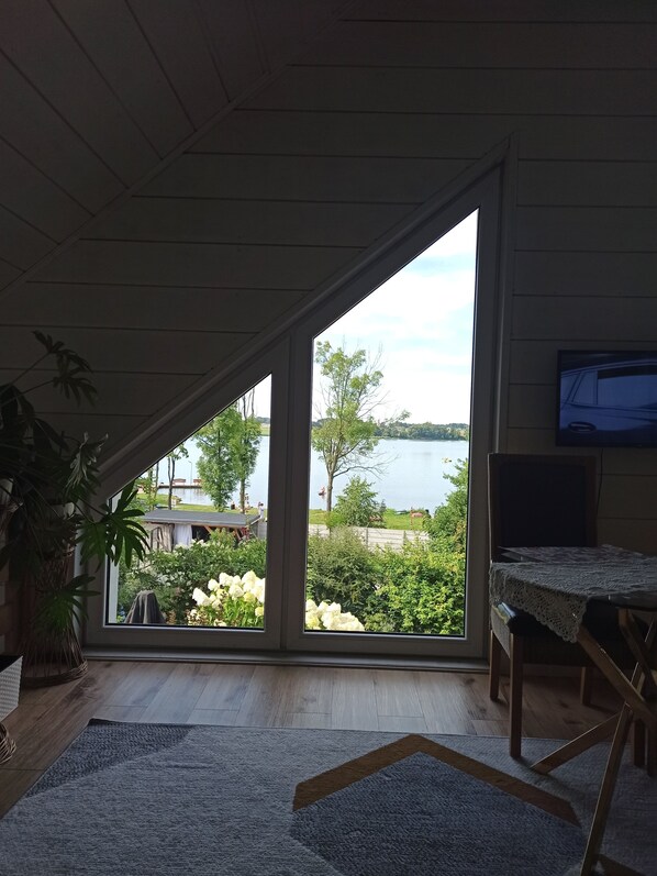 A room with a large window, a television, and a wooden floor.