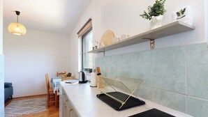 Een moderne keuken met een marmeren aanrechtblad, een zwart inductiekookplaat en een houten stoel.