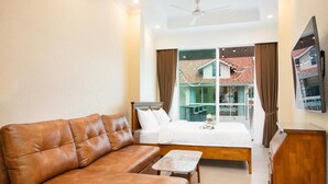 A modern hotel room with a leather sofa, a small table, a bed, and a large window offering a view of the outside. - Pratamnak Residence (Pattaya)