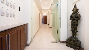 A hallway with a statue, a counter with cabinets, and a door with a glass panel. - Pratamnak Residence (Pattaya)