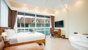 A modern hotel room with a large bed, a desk, a chair, a TV, and a bathtub. - Pratamnak Residence (Pattaya)
