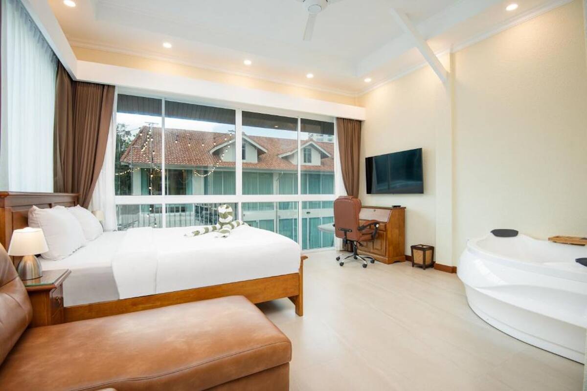 Une chambre d’hôtel moderne équipée d’un grand lit, d’un bureau, d’une chaise, d’une télévision et d’une baignoire.