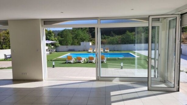 A spacious indoor area with a large sliding glass door leading to a pool and garden.