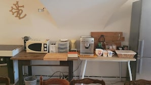 Eine kleine Küche mit Mikrowelle, Toaster, Kaffeemaschine und einem Esstisch.