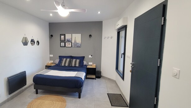 Ein modernes Schlafzimmer mit Bett, Nachttischen, Deckenventilator und Wandbildern.